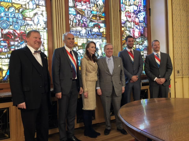 Eine Gruppe von Menschen, wahrscheinlich Mitglieder der Königlichen Familie, die vor einem Buntglasfenster stehen, mit einem Tisch im Vordergrund und einer Wand im Hintergrund.