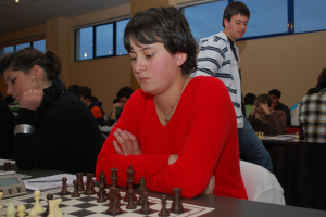 A group of people playing chess, with one person in a red dress at the center.