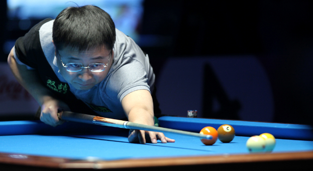 Eine Person hält einen Queue-Stock und zielt auf Snooker-Kugeln auf einem Tisch.