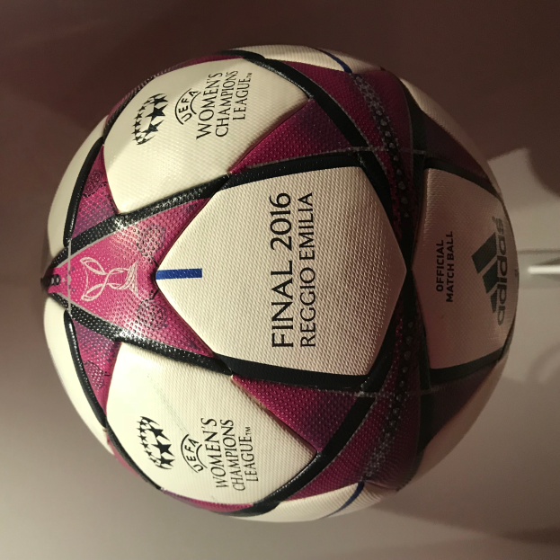 Ein Fußball auf einem weißen Tisch mit "UEFA Women's Champions League Final 2016" in weiß, rosa und schwarz geschrieben.