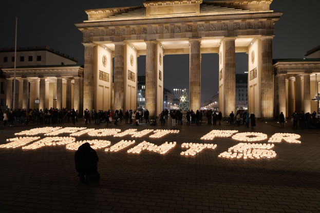 Eine Gruppe von Menschen vor dem beleuchteten Reichstagsgebäude in Berlin, Deutschland, mit der Aufschrift "Kampf für die Freiheit" auf dem Boden im Vordergrund.