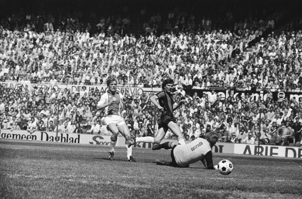 Schwarzes und weißes Foto von Männern, die auf einem Feld Fütbol spielen, mit Zuschauern im Hintergrund und einem Banner mit der Aufschrift "Bundesliga 1978-79 Ajax 1-1 Hannover 96".