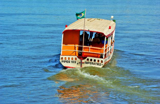 Ein Boot mit Menschen darin und eine Flagge mit Text fährt auf dem Wasser.