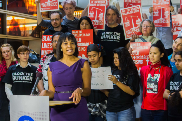 Eine Black-Lives-Matter-Aktivistin spricht vor einer Menge mit Schildern an einem Podium mit Mikrofon.