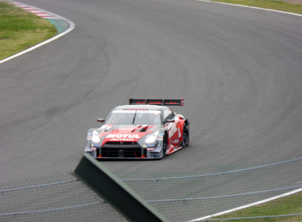 Nissan GT-R Nismo GT3 Rennauto auf der Nürburgring 24 Stunden Rennstrecke, umgeben von grünem Gras auf beiden Seiten.