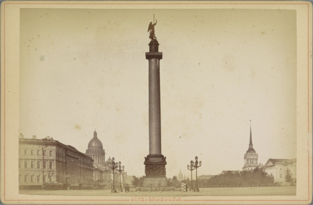 Altes Schwarz-Weiß-Foto eines Denkmals in einem städtischen Platz, eingerahmt von Gebäuden, Straßenmöbeln, Bäumen und einem klaren Himmel, mit Text entlang der unteren Kante.