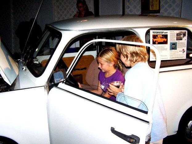 Zwei Kinder versuchen in ein Auto mit mehreren anderen Menschen in der Nähe zu steigen.