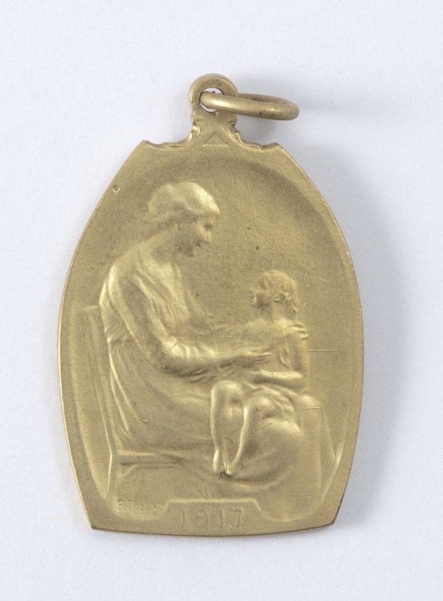 Goldmedaille mit einer Gravur einer Frau in einem weißen Kleid mit einem Dutt, die ein Kind hält, beide schauen sich mit Ausdrucken von Zärtlichkeit und Verwunderung an, beschriftet mit "Mutter und Kind" in Schreibschrift.