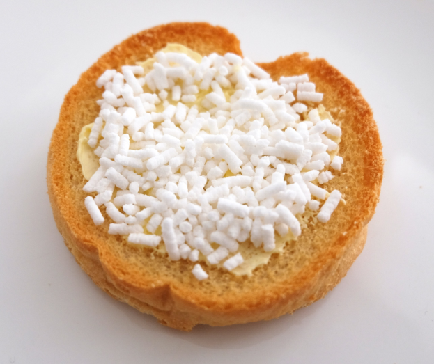 Herzförmiger Brotschnitt mit Butter und Zucker auf einer weißen Oberfläche.