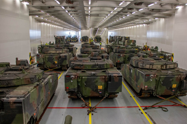 Ein grosser Militaraerraum mit Reihen von Militaraerfahrzeugen, Wanden auf beiden Seiten und Deckenleuchten.