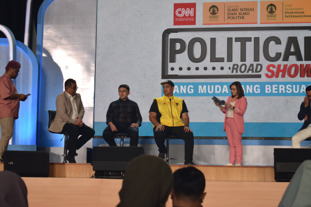 Eine Gruppe von Menschen sitzt auf einer Bühne mit einigen, die auf einem Podium stehen, und ein Schild im Hintergrund mit der Aufschrift "Cnn Political Road Show".