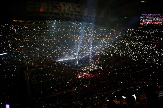 Gro├če Menge in hell erleuchtetem Stadion bei Nacht mit einem Bildschirm auf der rechten Seite, der die Ergebnisse der Super Bowl XLVII-Halbzeitpause anzeigt.