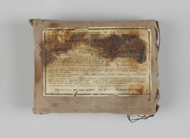 Ein kleiner Beutel mit einem Stück Papier oben drauf, wahrscheinlich ein Verbandskasten, mit Text darauf geschrieben.
