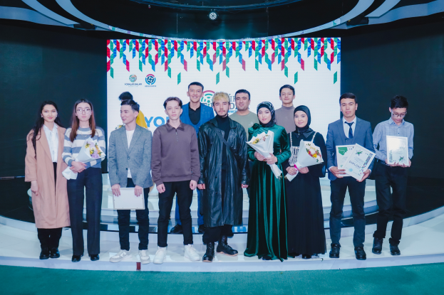 Eine Gruppe von Menschen auf einer Bühne, jeder hält einen Blumenstrauß und Urkunden in der Hand, im Hintergrund ein Schild mit der Aufschrift "Youth Solar Awards 2019".