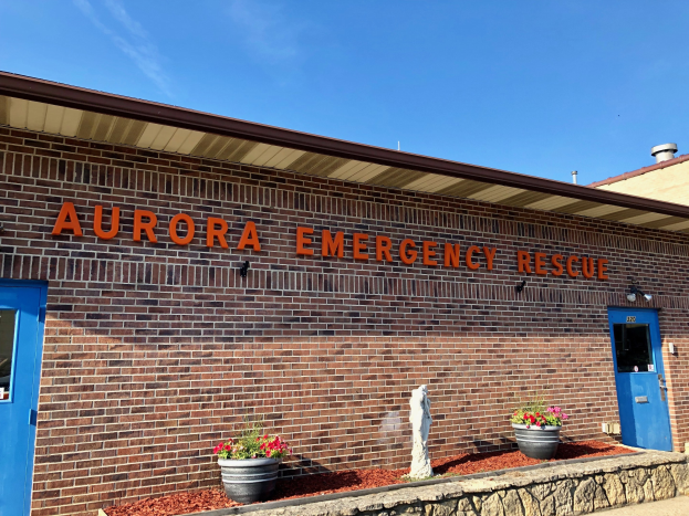 Außenansicht des Aurora Emergency Rescue Gebäudes in Aurora, Colorado, mit einer Backsteinfassade, Türen, Fenstern, einer Namensplakette, Topfpflanzen und einer Statue davor.