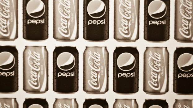 Zwei Dosen Soda, eine Pepsi und eine Coca-Cola, nebeneinander gestellt.