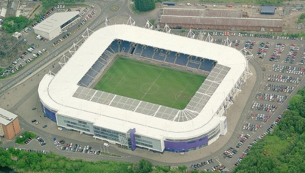 Luftbild des Fußballstadions von Tottenham Hotspur, umgeben von Stadtgebäuden, Bäumen und Straßen mit Fahrzeugen.