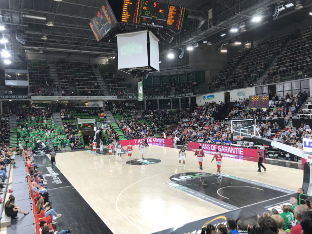 Basketballspiel zwischen Asvel und Galatasaray in einem vollen Indoor-Stadion mit Anzeigetafeln, die das Match-up anzeigen.