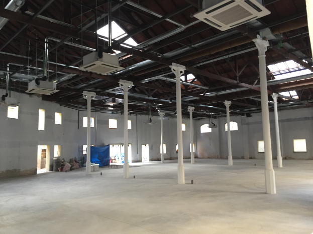 Ein große Lagerhalle-Inneneinrichtung mit zahlreichen Fenstern, Säulen, einem gefliesten Boden, einer hohen Decke mit Lichtern und Klimaanlagen und verschiedenen Gegenständen, zur Vermietung verfügbar.