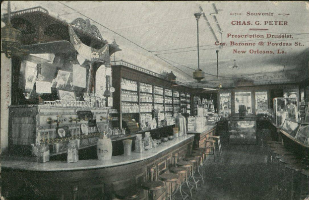 Ein altes Schwarz-Weiß-Foto einer Apotheke in New Orleans, Louisiana, mit Hockern und Tischen mit Flaschen und Gegenständen im Vordergrund, Glasfenstern auf der rechten Seite und Text oben.