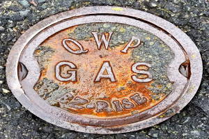 Ein Metallgullydeckel auf dem Boden mit der Aufschrift "QWP Gas".