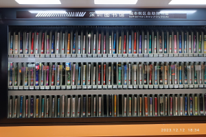 Eine gut beleuchtete Bibliothek mit hohen Bücherregalen voller Bücher, mit einer Tafel mit Text und einem Wasserzeichen unten.