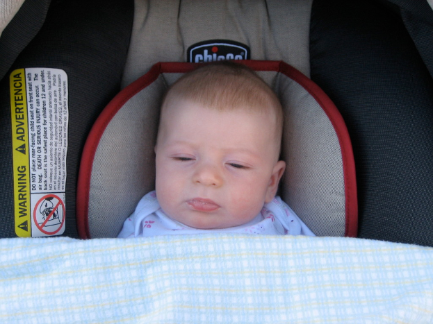 Ein Baby unter einer Babywiege mit einem Warnaufkleber auf der linken Seite.