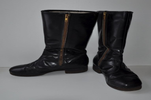 Schwarze Lederstiefel mit silbernen Reißverschlüssen auf einer weißen Oberfläche, mit einem glatten, glänzenden Finish.