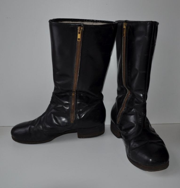 Schwarze Lederstiefel mit silbernen Reißverschlüssen auf einer weißen Oberfläche, mit einem glatten, glänzenden Finish.