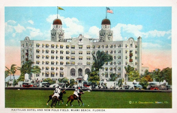 Postkarte des Nautilus Hotels und des neuen Polo Felds in Miami Beach, Florida, das ein Gebäude mit Fenstern, Bäumen, Fahrzeugen, Menschen und einen bewölkten Himmel zeigt, mit Text am unteren Rand.
