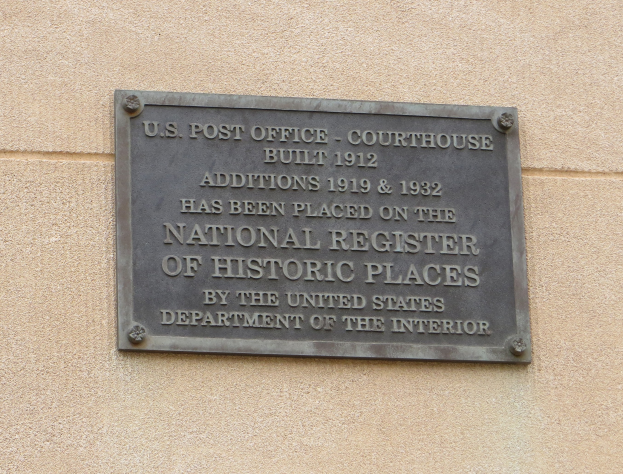 Metallplatte an einer Gebäudewand mit der Aufschrift "National Register of Historic Places" in fetter schwarzer Schrift.