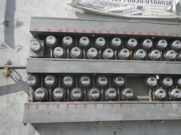 Nahaufnahme eines Stromzählers an der Seite eines Gebäudes mit einem Banner oben mit Text