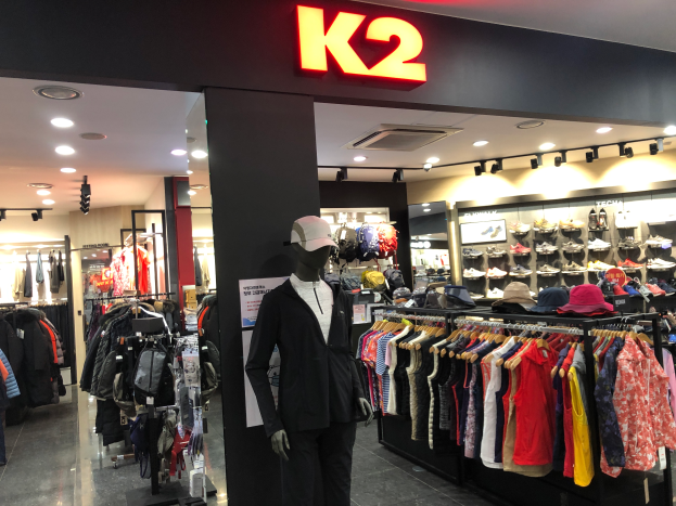 Ein K2-Kleidungsgeschßt in Singapur mit Puppen in Kappen, Körper auf Bühgeln, Schuhe auf Röcken und einer Wandtafel mit Text.