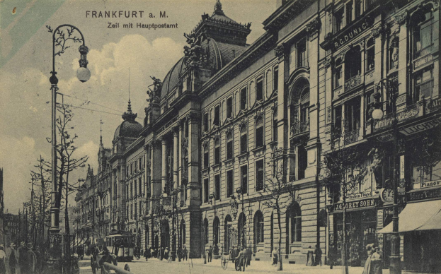Ein Schwarz-Weiß-Foto einer Straßenkreuzung in Frankfurt, Deutschland, das Menschen zeigt, die auf Bänken stehen und sitzen, Fahrzeuge auf der Straße, Gebäude mit Fenstern, Schilder, Pfosten, Bäume und einen bewölkten Himmel.